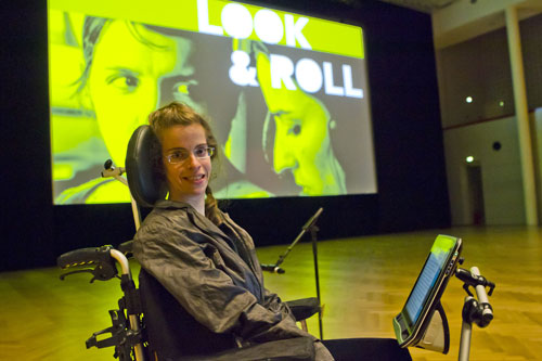 Foto der Veranstaltung in Bonn: Frau in Rollstuhl, im Hintegrund das Logo der Veranstaltung